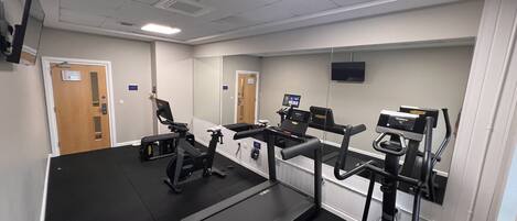 Un centre de remise en forme équipé de tapis de course, de vélos elliptiques et d’un vélo d’appartement.
