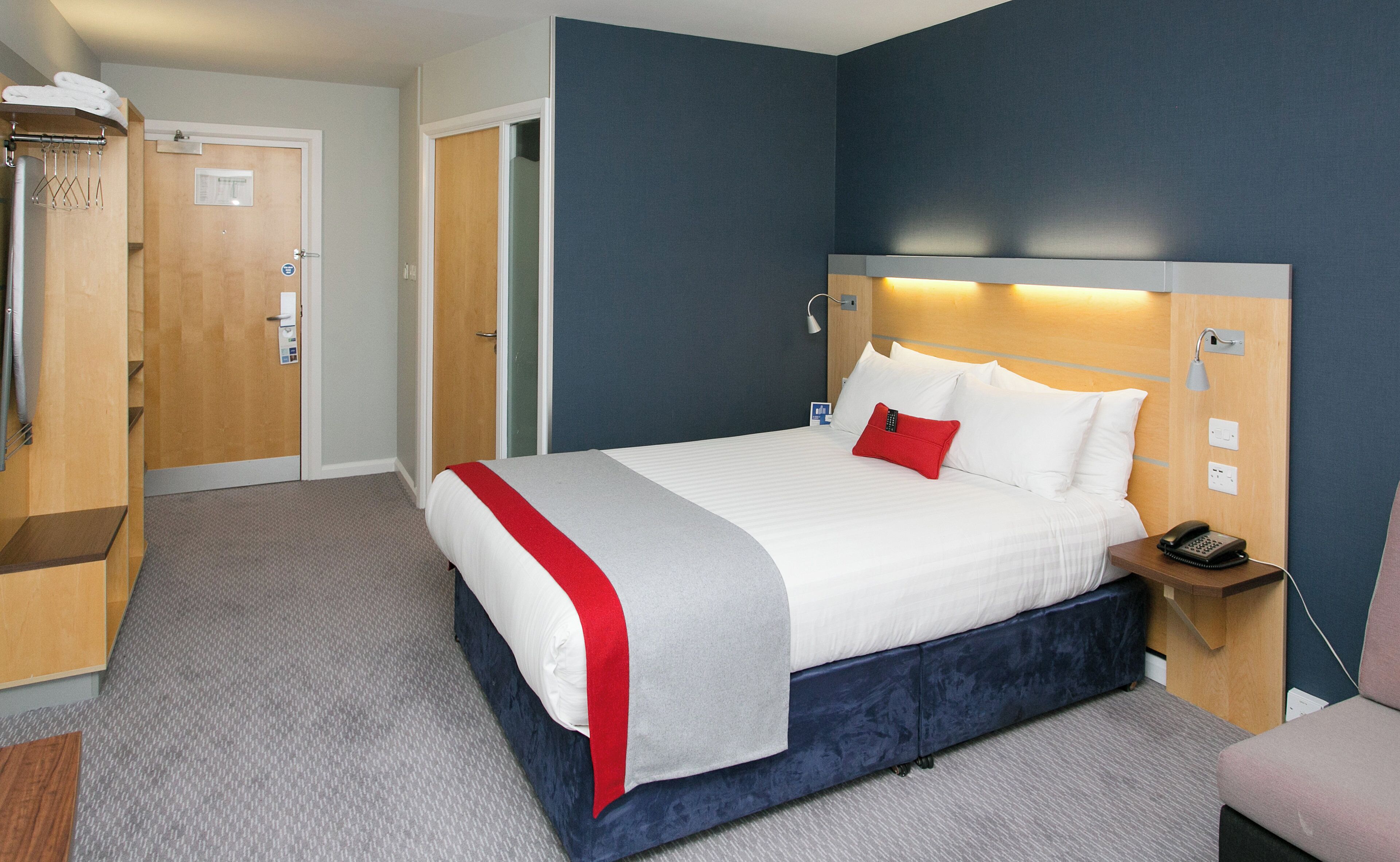 Quarto de hotel com cama, mesa de cabeceira e guarda-roupa.