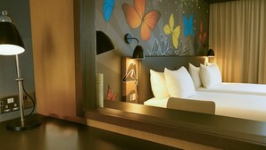 A hotel room with a bed, bedside lamps, a mirror, and a wall with butterfly art. - Holiday Inn Salisbury - Stonehenge by IHG (Salisbury)