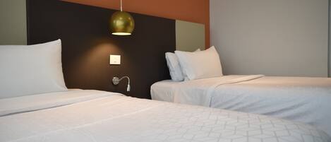 A hotel room with two beds, a modern pendant light, and a wall-mounted light switch.