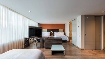 Una habitación de hotel moderna con una cama grande, televisión, escritorio y sofá.