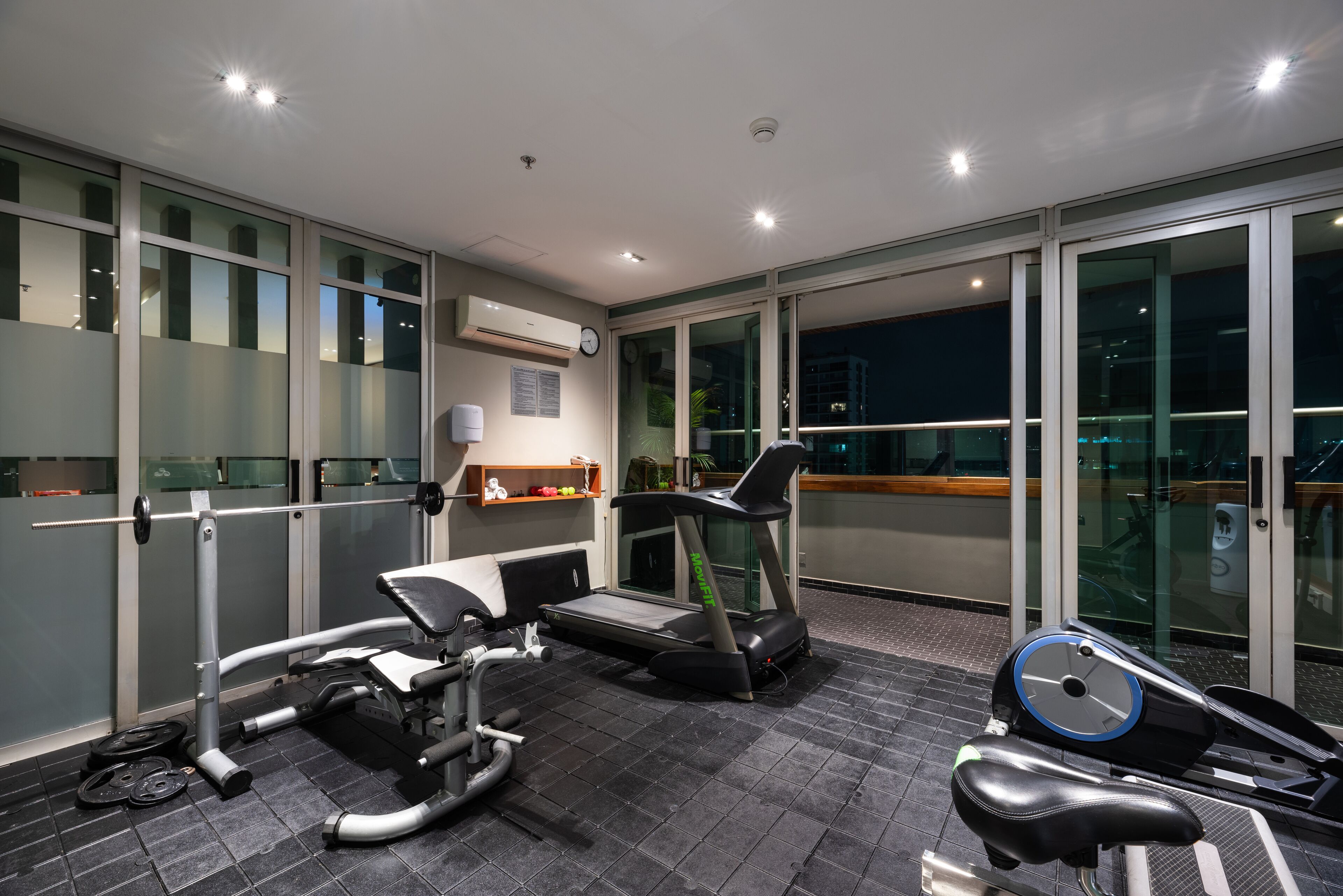 Un gimnasio moderno con cinta de correr, banco de pesas y bicicleta estática.