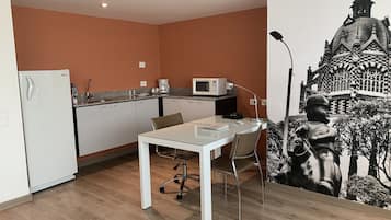 A compact kitchen with a white refrigerator, microwave, and coffee maker on the countertop.