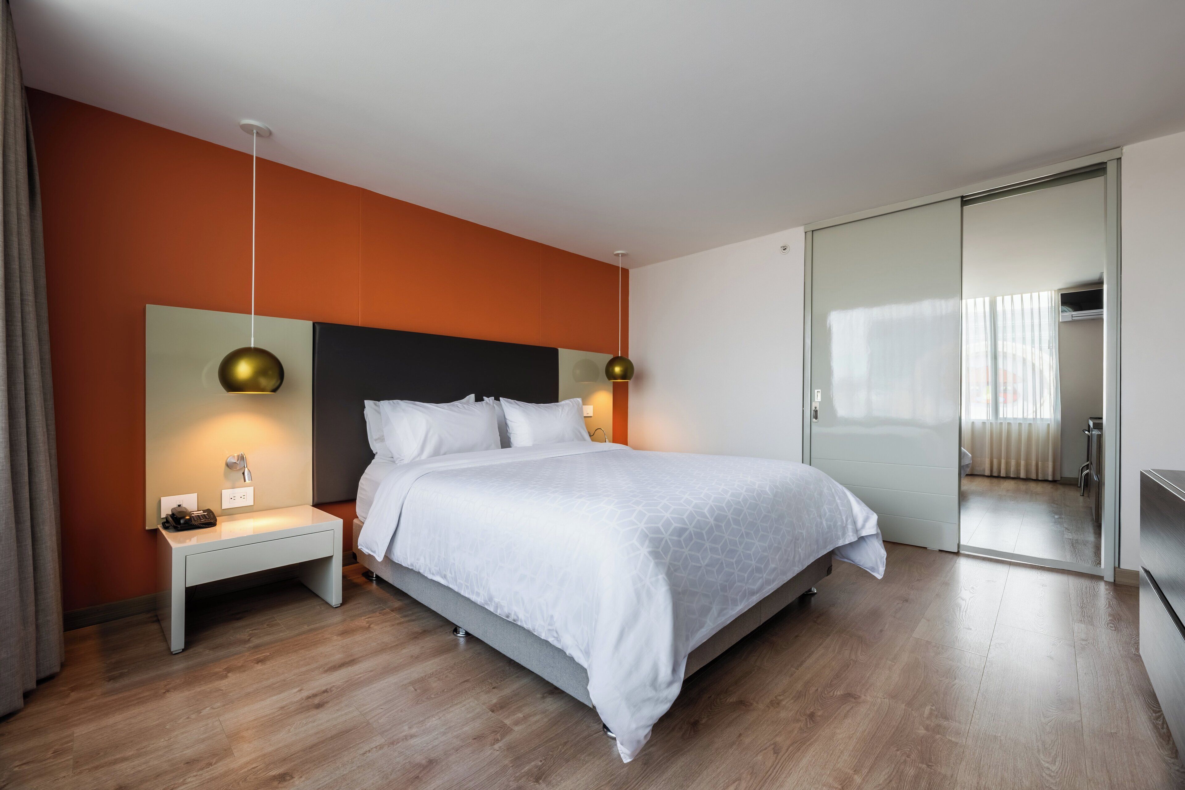 A modern bedroom with a bed, bedside tables, and a wardrobe.