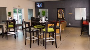Un restaurant avec plusieurs tables et chaises, un téléviseur fixé au mur et un juke-box également fixé au mur.