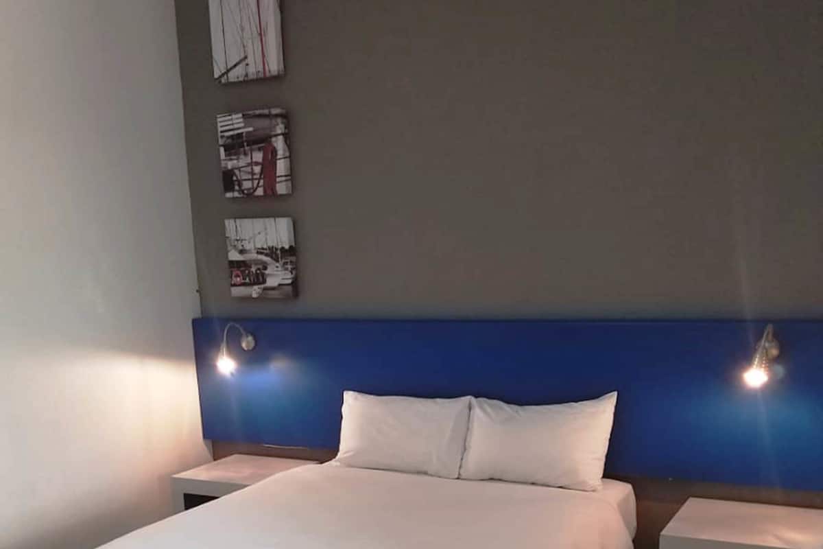 A hotel room with a large bed, two bedside tables, and a blue headboard.