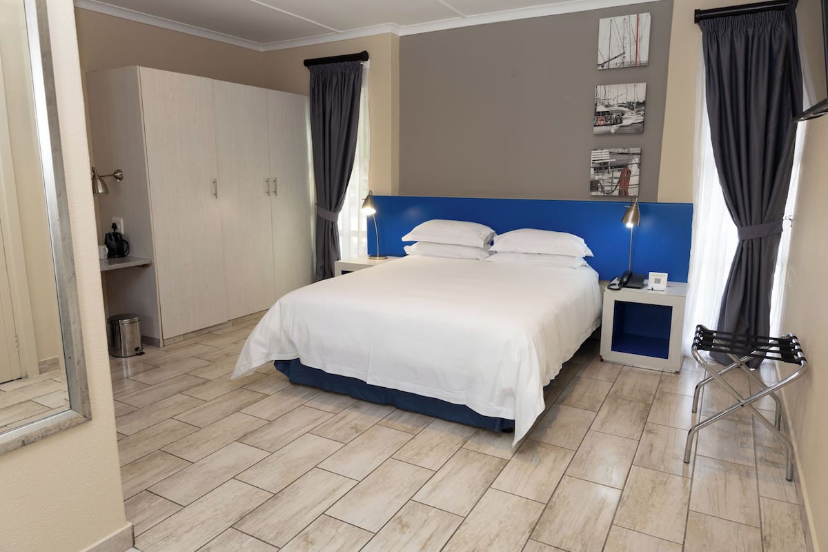 A neatly arranged bedroom with a bed, bedside tables, and a wardrobe.
