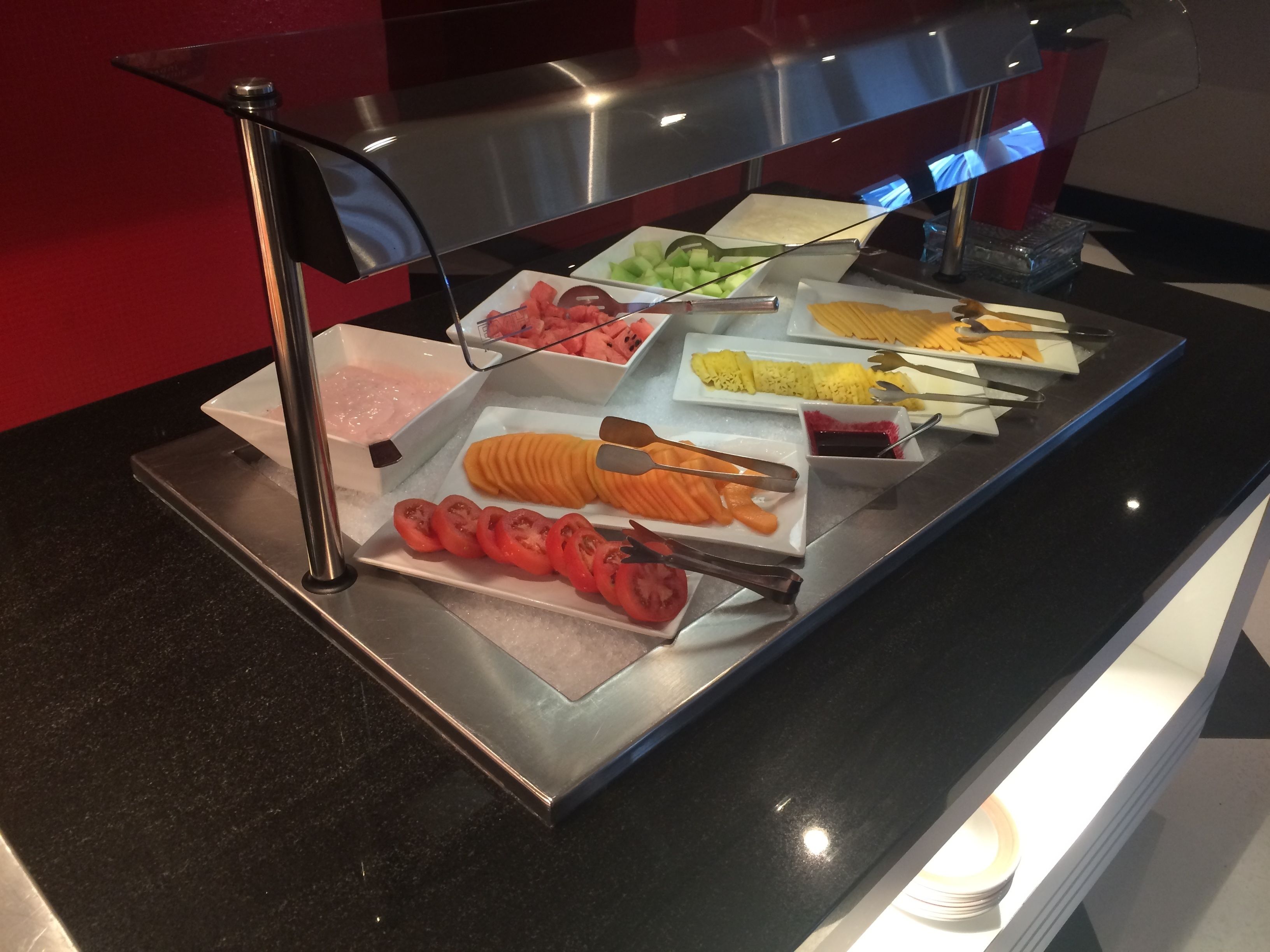 A buffet with various food items including sliced tomatoes, carrots, and other vegetables.