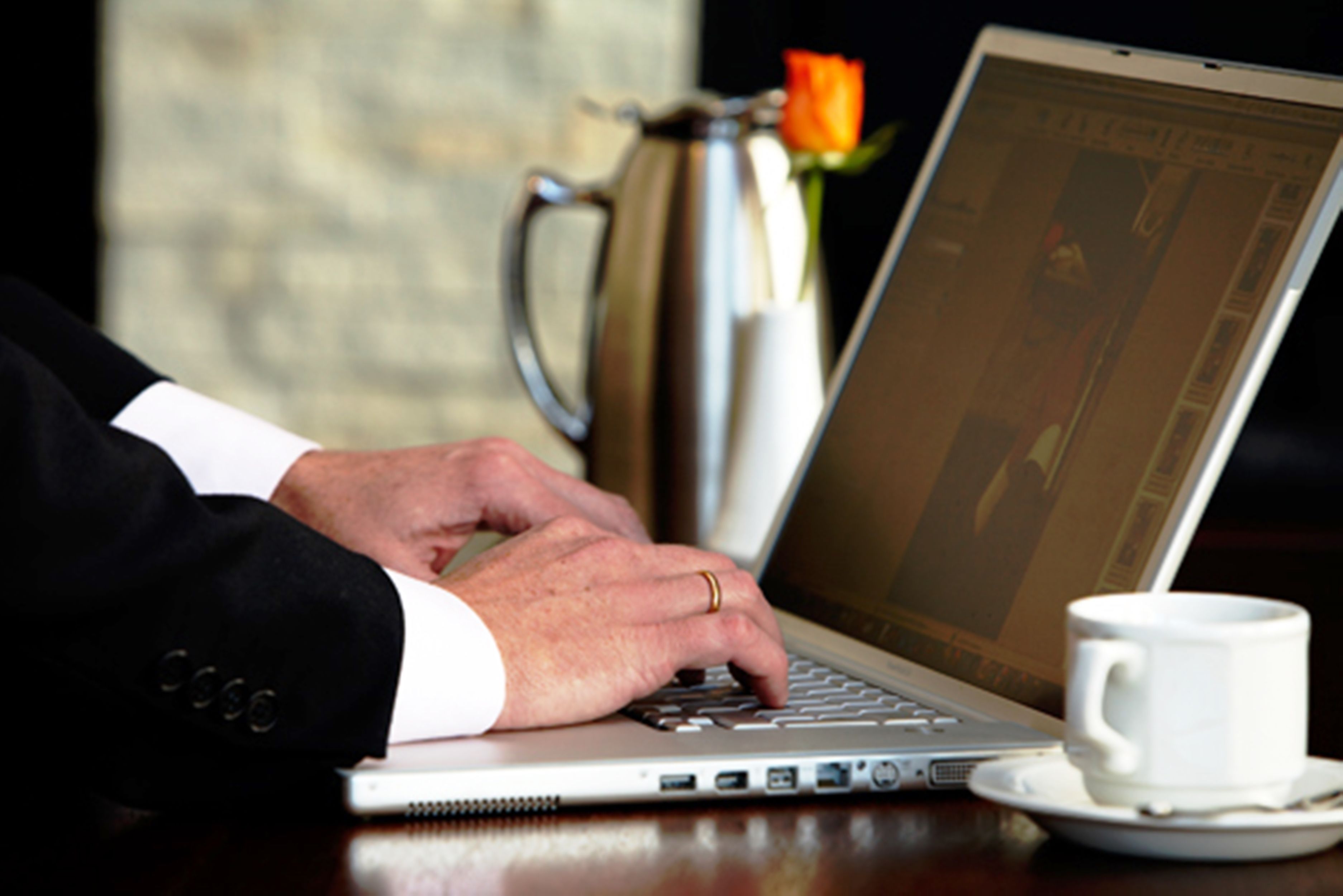 A laptop on a table with a coffee cup beside it.