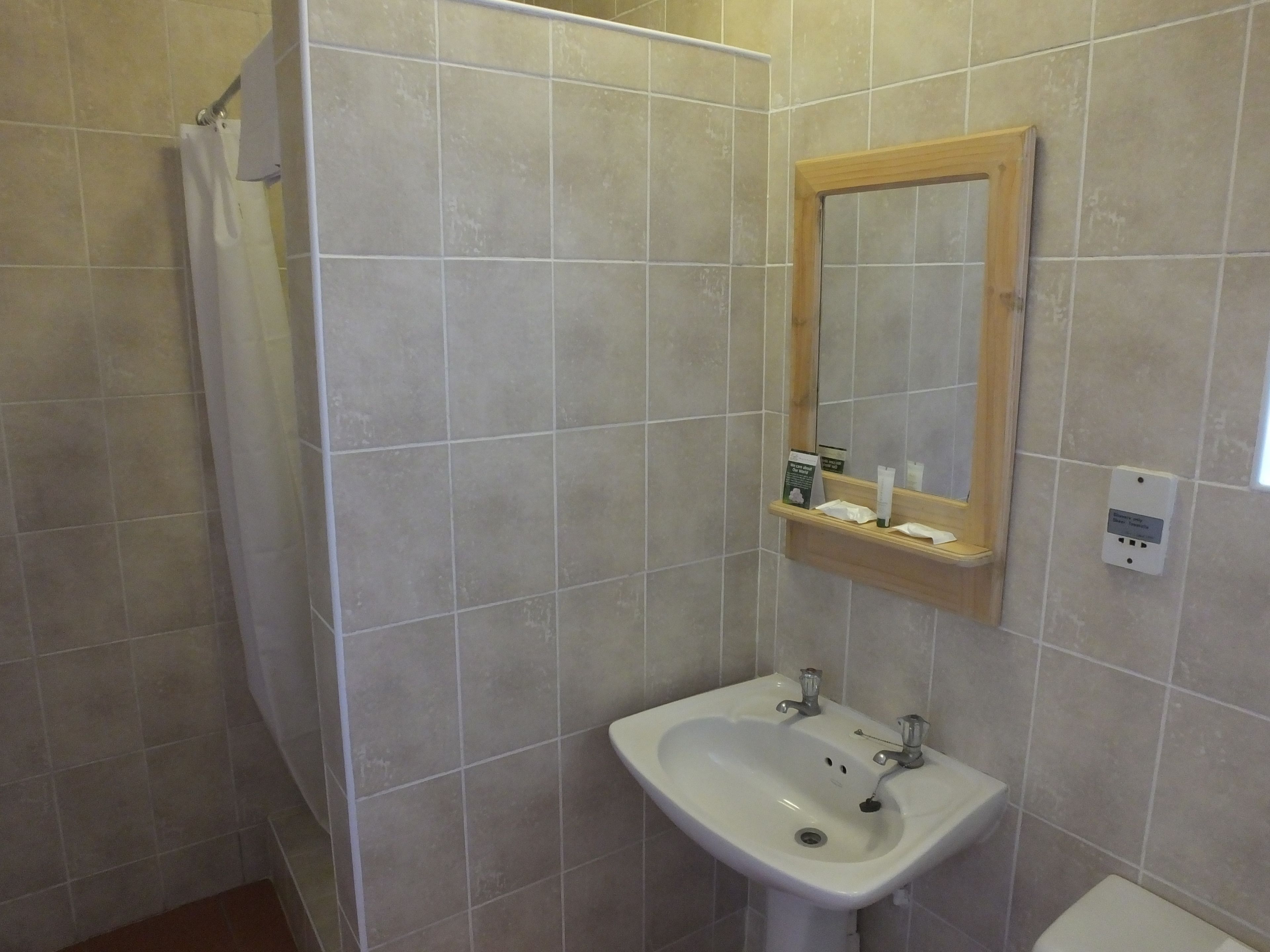 Un baño con lavamanos blanco, un espejo y una ducha.