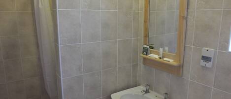 Un baño con lavamanos blanco, un espejo y una ducha.