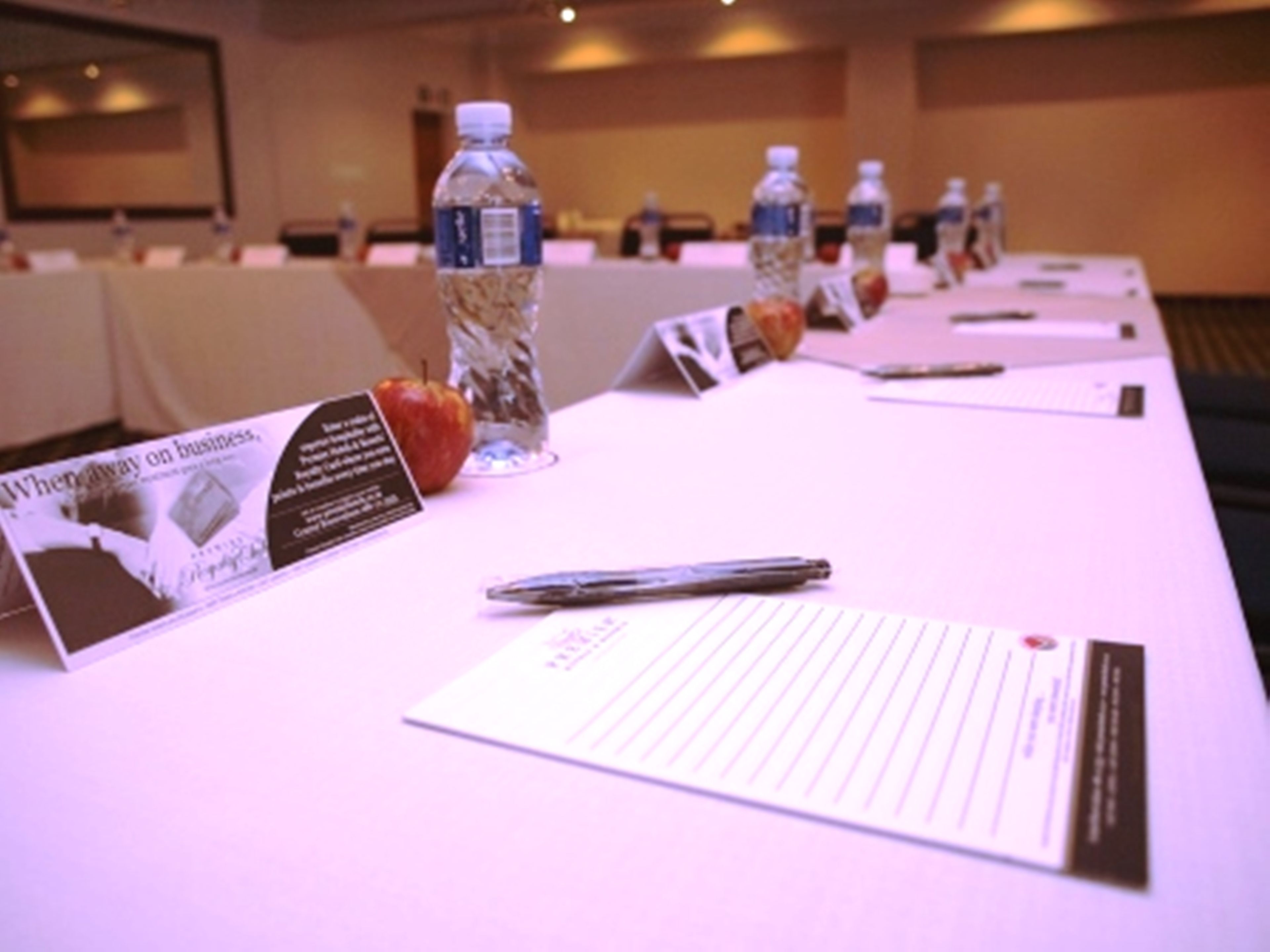 A conference table with nameplates, water bottles, and a pen.