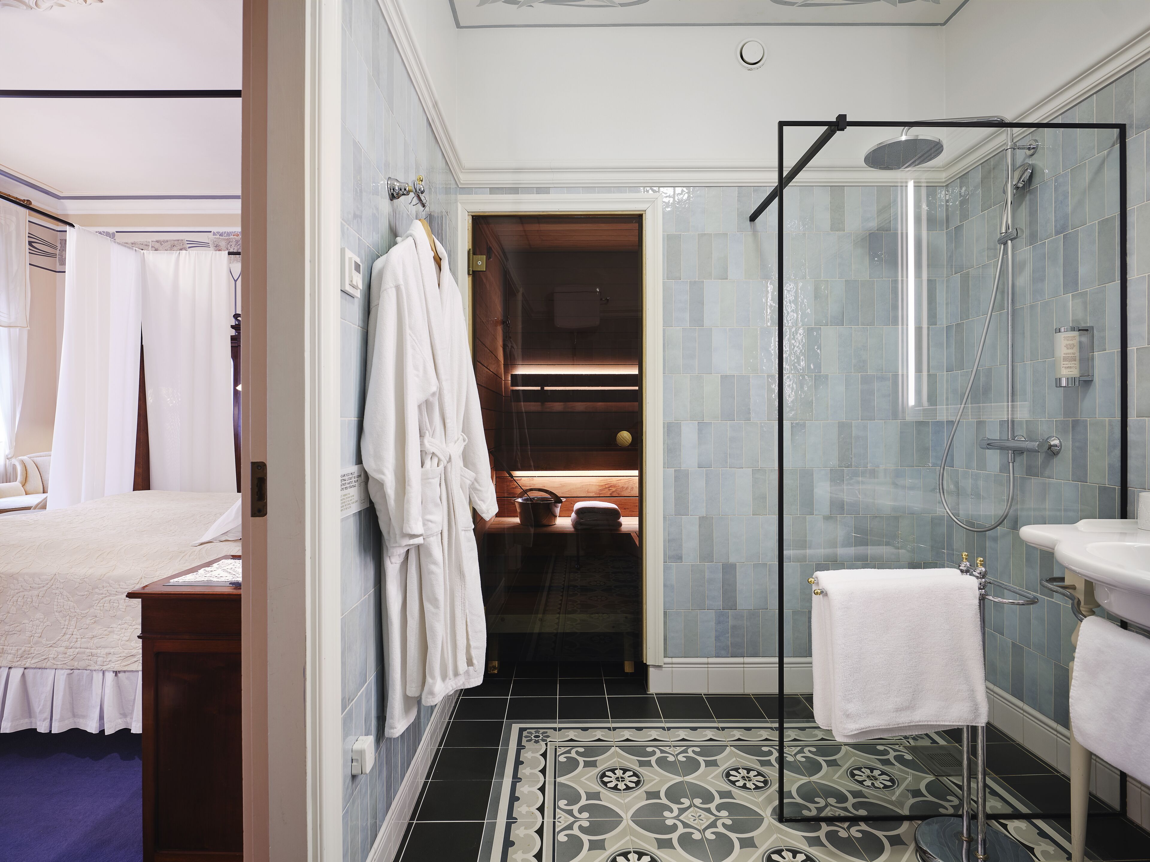 Un baño de hotel con ducha de vidrio, lavamanos y espejo.