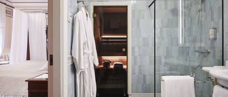Un baño de hotel con ducha de vidrio, lavamanos y espejo.