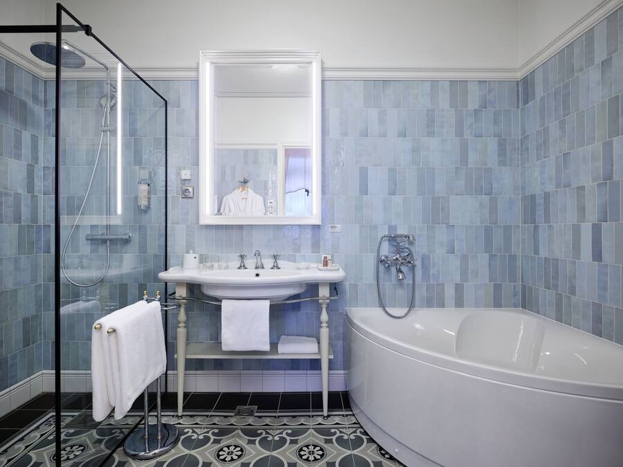 A bathroom with a bathtub, a glass-enclosed shower, and a sink with a mirror above it.