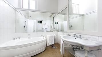 A modern bathroom with two sinks, a bathtub, and a large mirror.