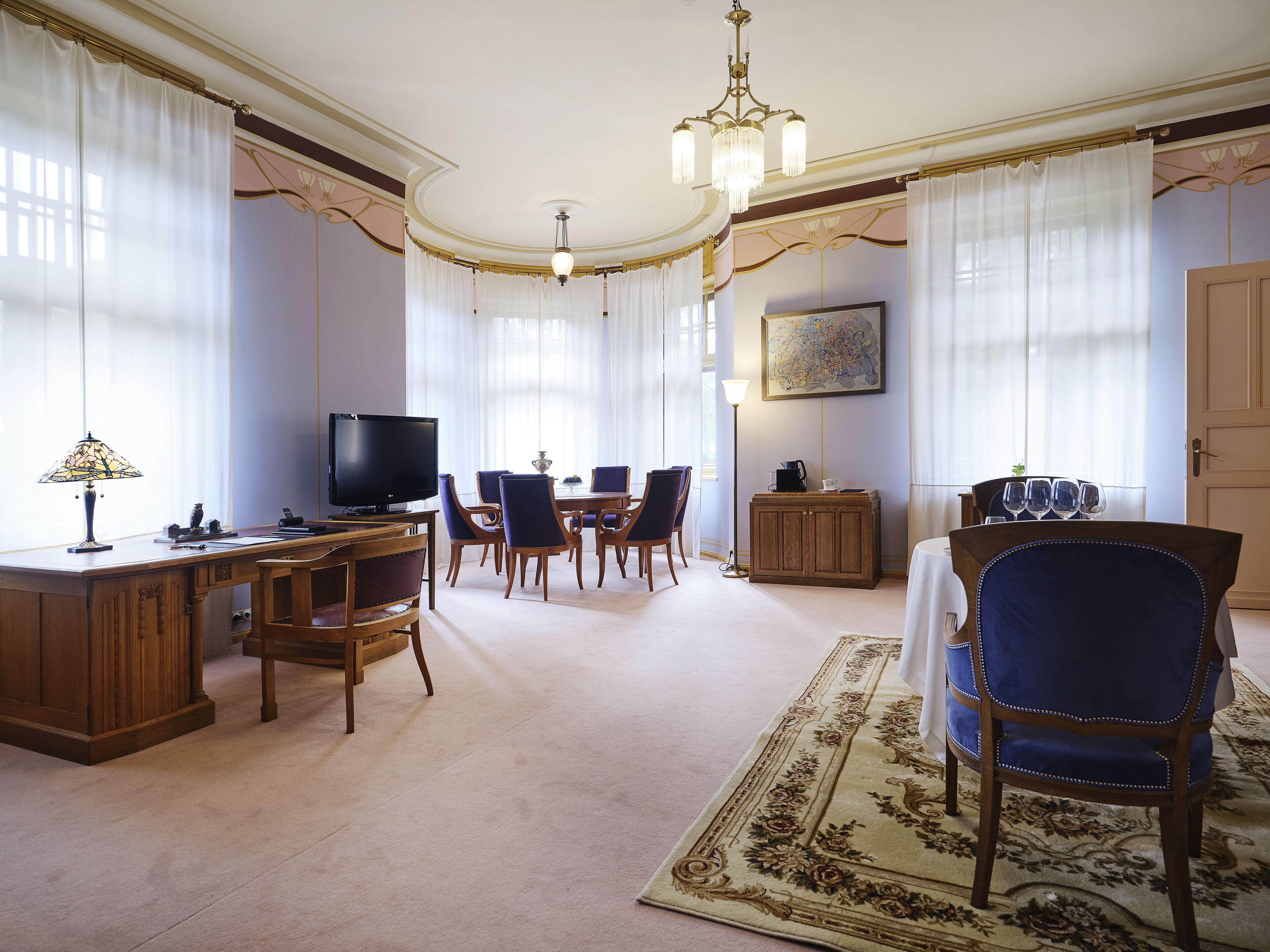 Ein geräumiges Wohnzimmer mit Fernseher, Essbereich und einem großen Teppich.