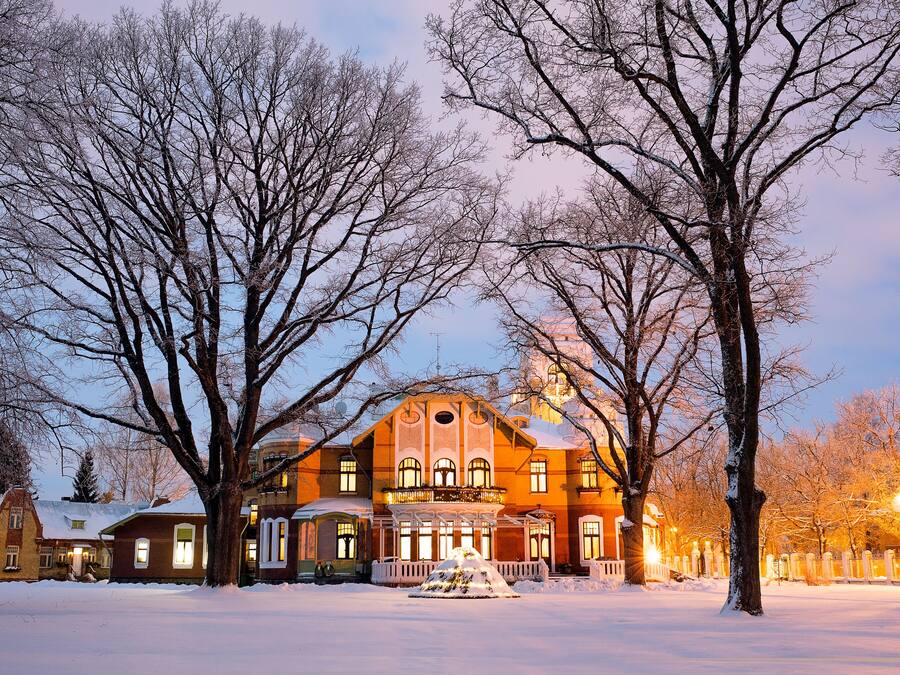 Un edificio grande e histórico con muchas ventanas y un césped cubierto de nieve.