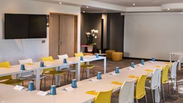 A modern conference room with white tables, yellow and white chairs, and blue nameplates.
