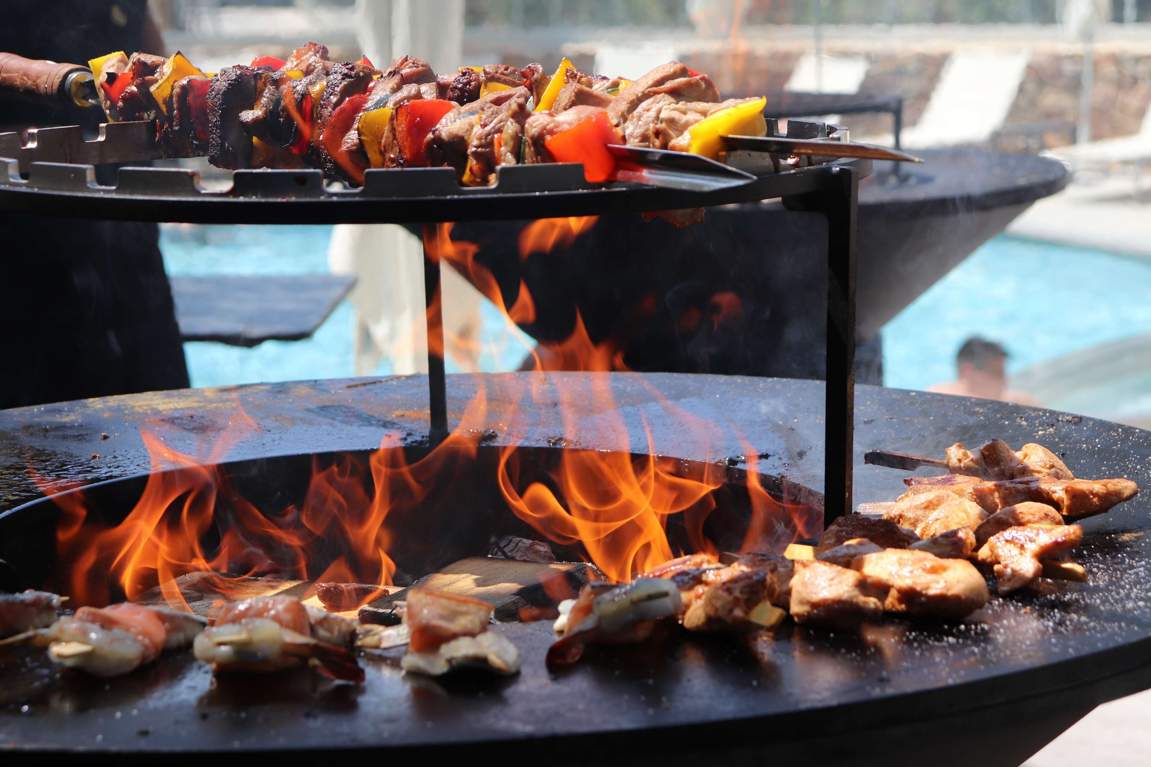 A grill with meat skewers and flames.