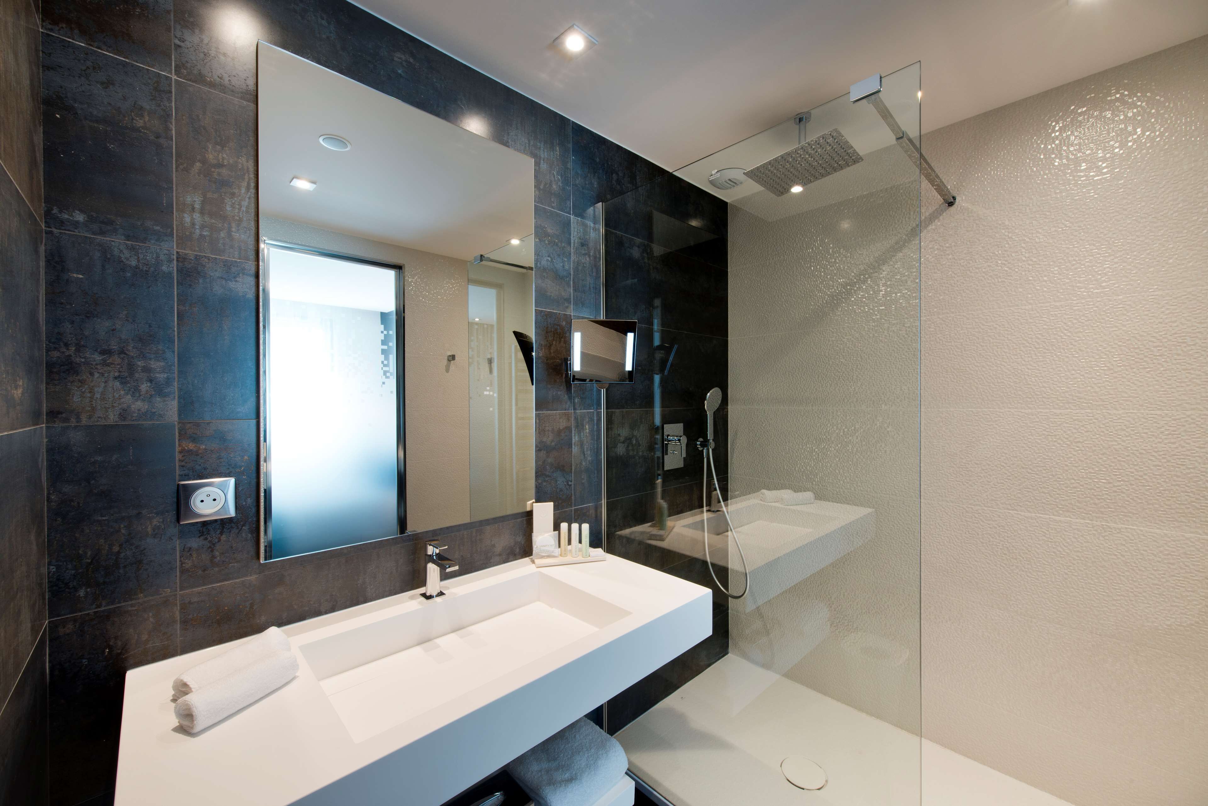 A modern bathroom with two sinks, a large mirror, and a glass-enclosed shower.