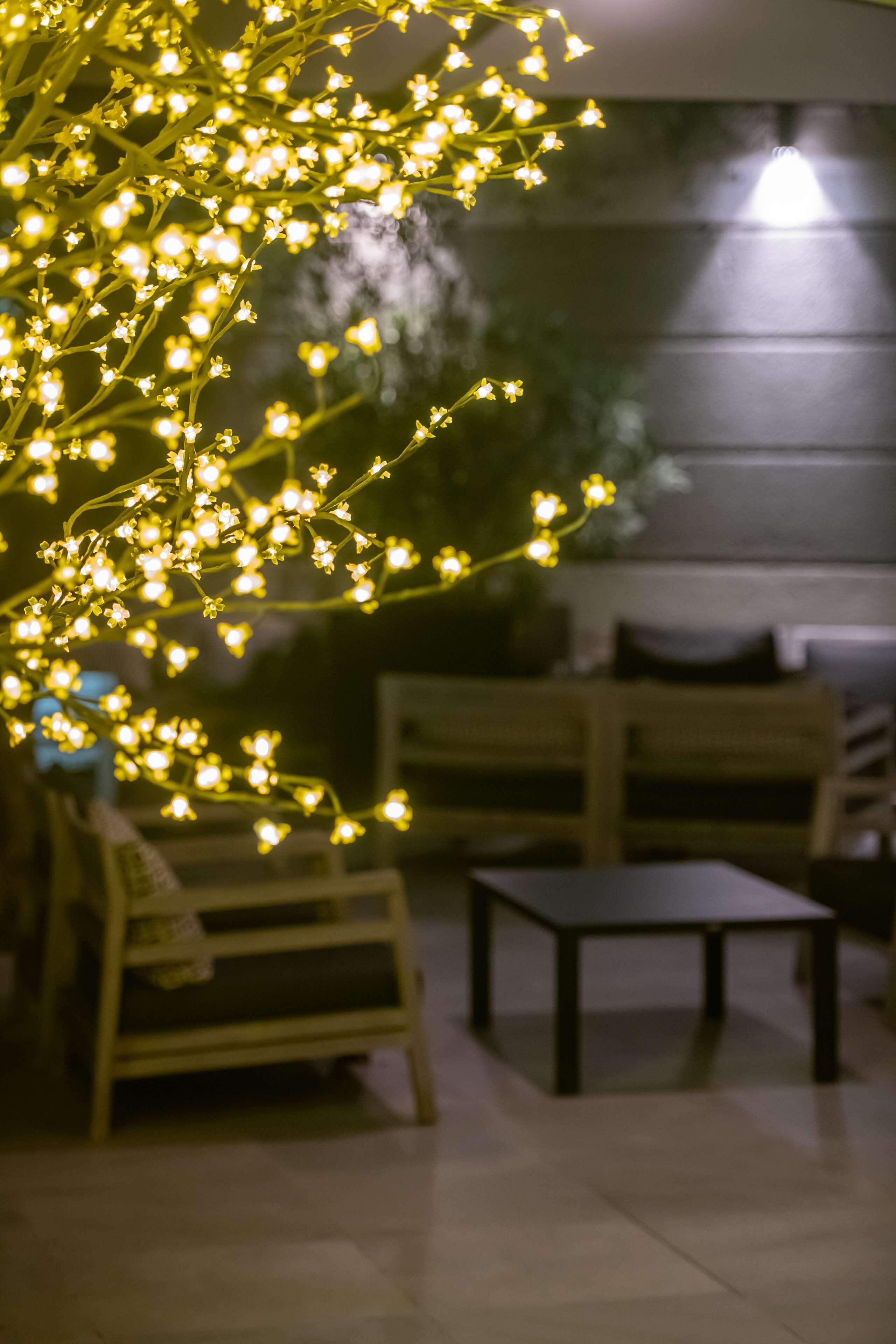 Un espace détente avec un banc en bois et une petite table, éclairé par des guirlandes lumineuses.