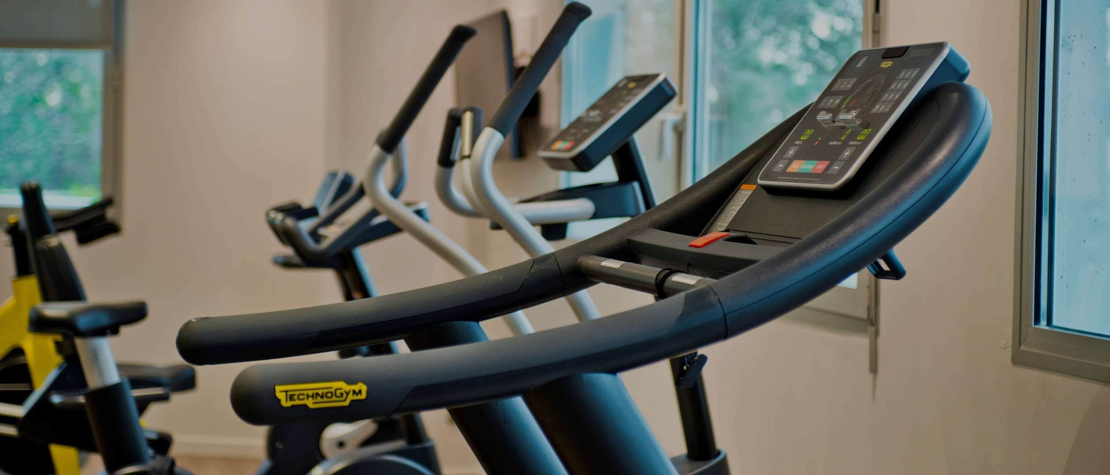 Une rangée de vélos d’appartement équipés d’écrans numériques, probablement dans une salle de sport.