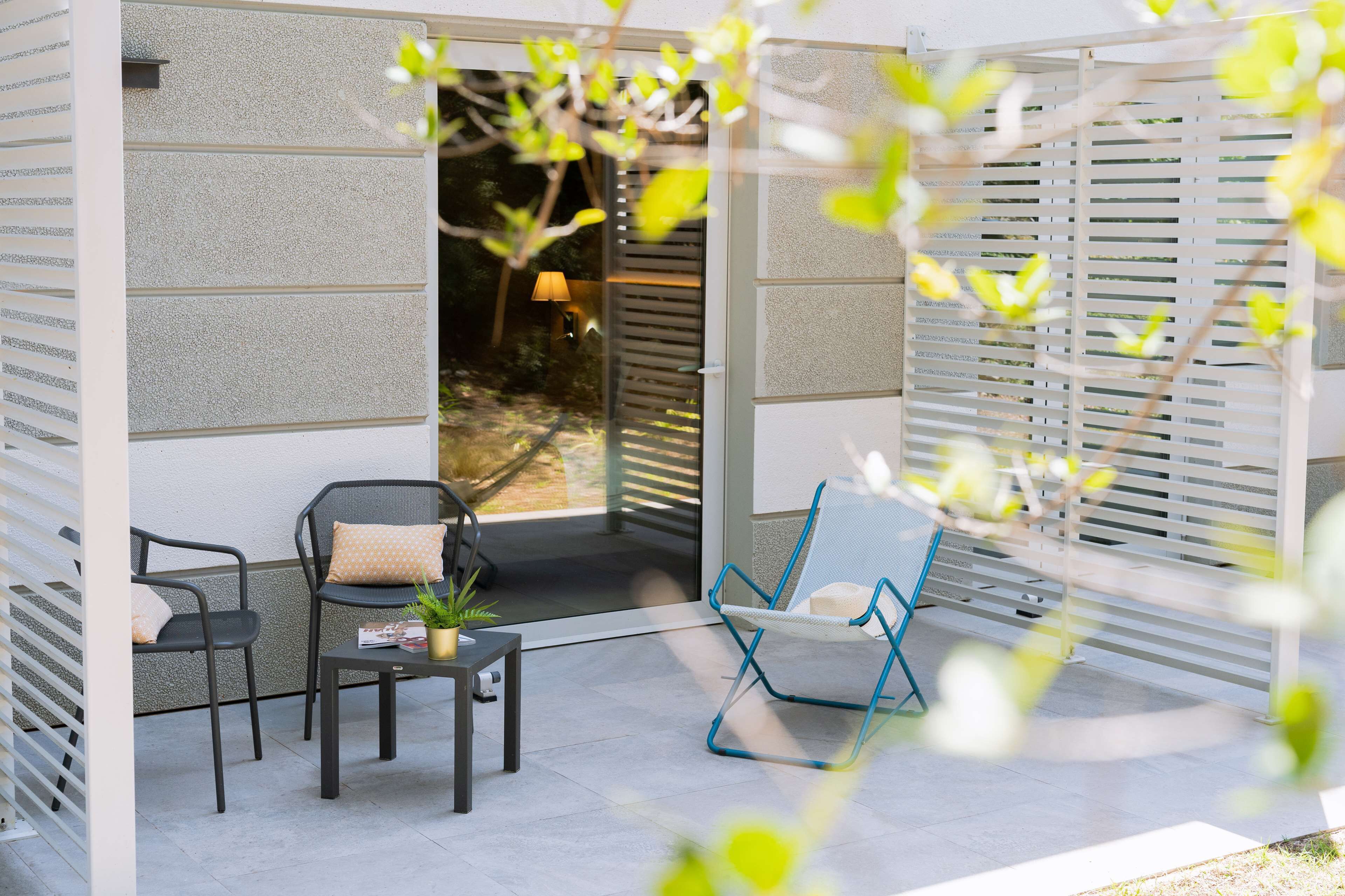 Un espace extérieur aménagé avec deux chaises, une table et un pot de fleurs.