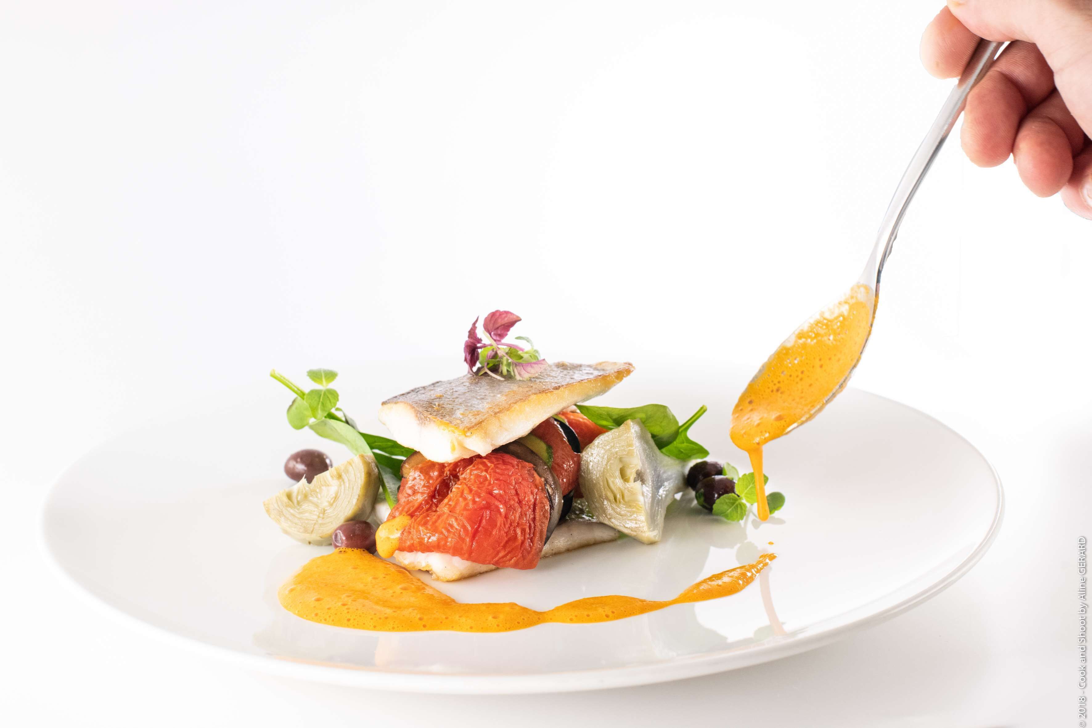 Un plato con un filete de pescado, verduras y salsa.