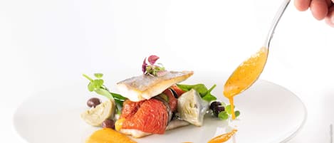 Un plato con un filete de pescado, verduras y salsa.