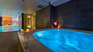 Un área de piscina interior moderna con un jacuzzi climatizado, paredes de azulejos e iluminación ambiental.