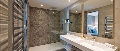 A modern bathroom with a large mirror, two sinks, and a shower area.