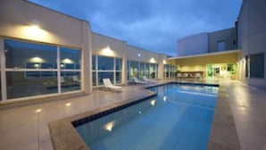 Una piscina interior con sillones de descanso y ventanas amplias.