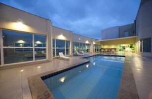 Una piscina al aire libre, sombrillas, sillones reclinables de piscina