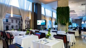 Un restaurante con mesas dispuestas para comer, una pantalla de televisión y vistas a un edificio.
