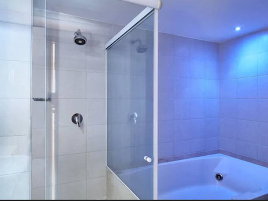 A modern bathroom with a glass-enclosed shower, a bathtub, and tiled walls.