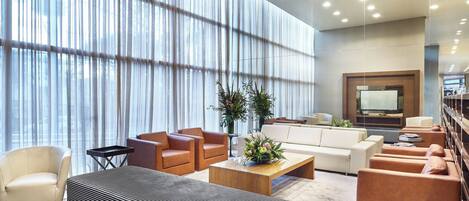A modern living room with a sofa, armchairs, a coffee table, and a TV.