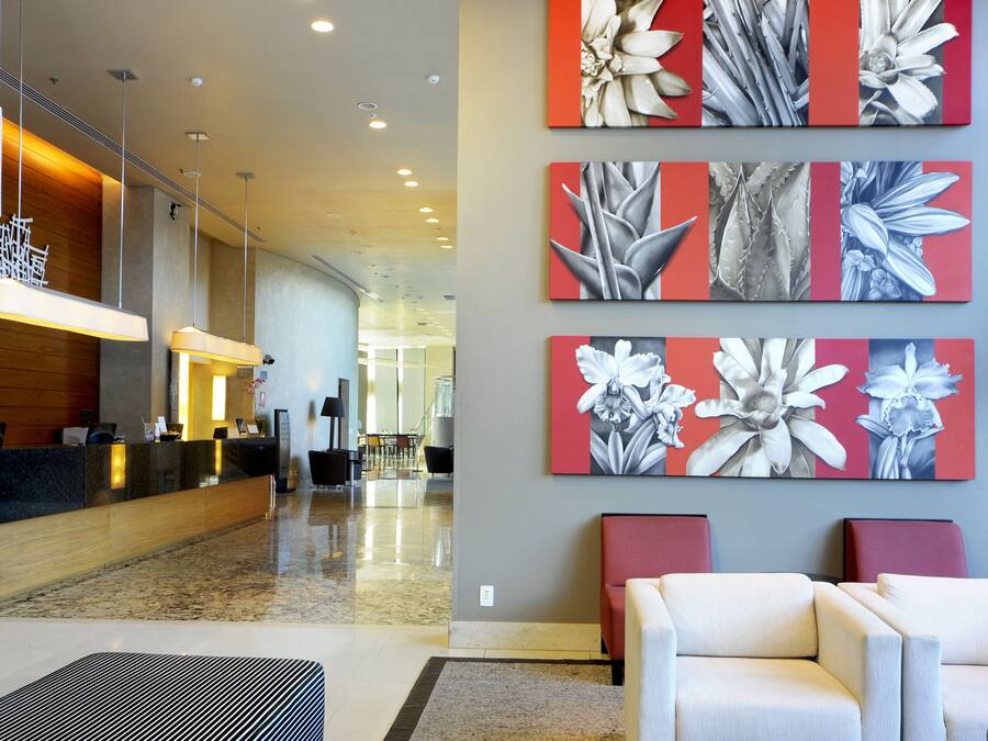 Un vestíbul d'hotel amb una recepció, zona d'estar i una obra d'art a la paret.