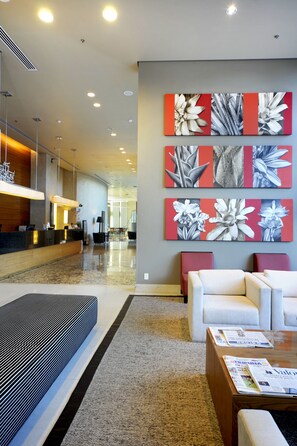 A hotel lobby with a reception desk, seating area, and artwork on the wall. - Sheraton Vitoria Hotel (Vitoria)