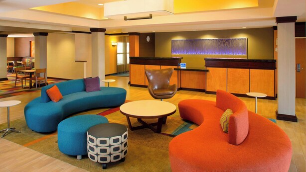 A modern lobby with a curved blue sofa, a round orange chair, and a small white table.
