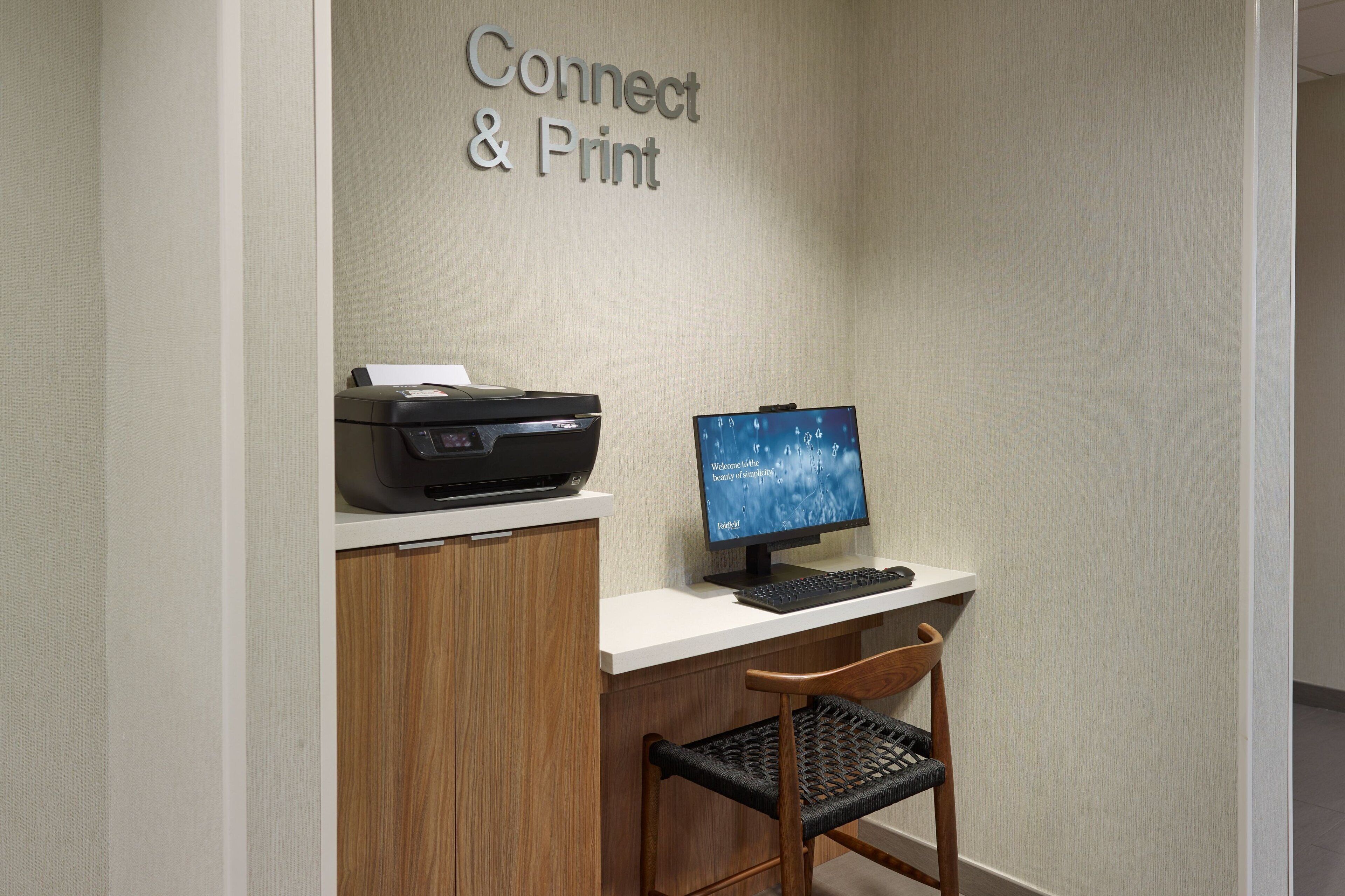 A workspace with a printer, computer, and a chair.