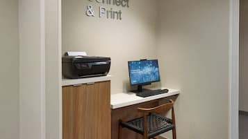 A workspace with a printer, computer, and a chair.
