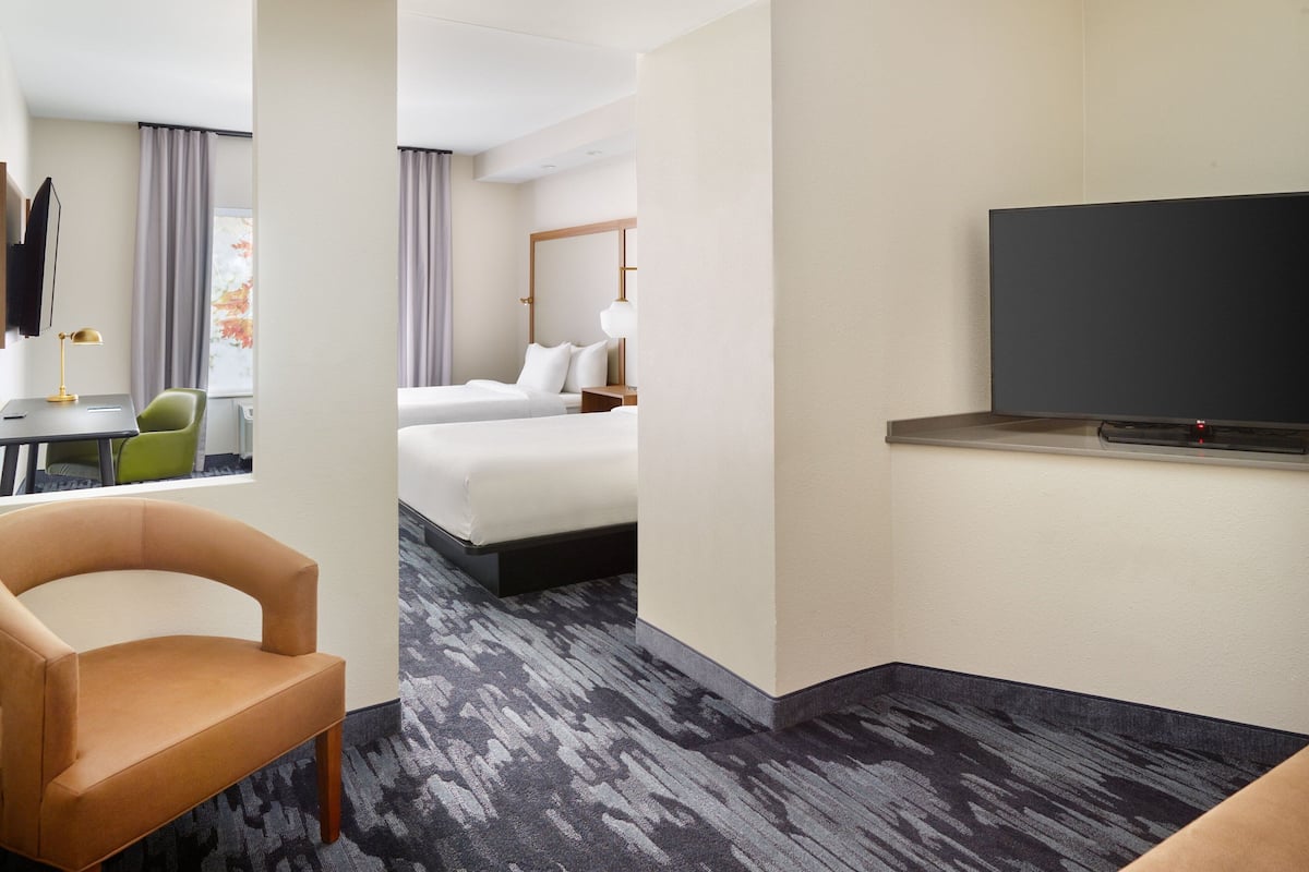 Een hotelkamer met een bed, een televisie, een bureau met stoel en een vloerbedekking.