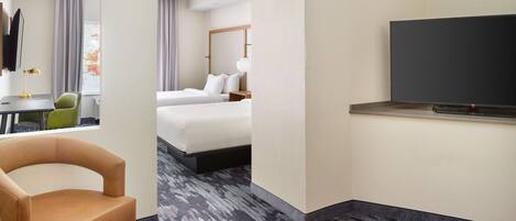 A hotel room with a bed, a TV, a desk with a chair, and a carpeted floor.