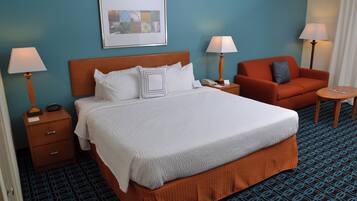 Una habitación de hotel con una cama grande, dos mesitas de noche, un sofá y una pequeña mesa redonda.
