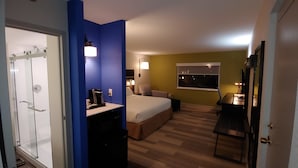 Ein Hotelzimmer mit Dusche, Bett, Schreibtisch und Fenster.
