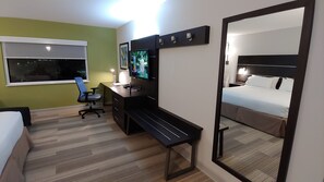 Une chambre d’hôtel avec un lit, un bureau, une chaise, une télévision et un miroir.
