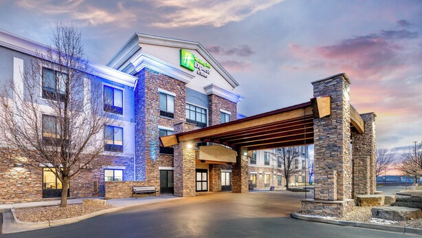 Un hôtel avec une façade en pierre, une entrée couverte et une enseigne indiquant qu’il s’agit d’un Hilton Express.