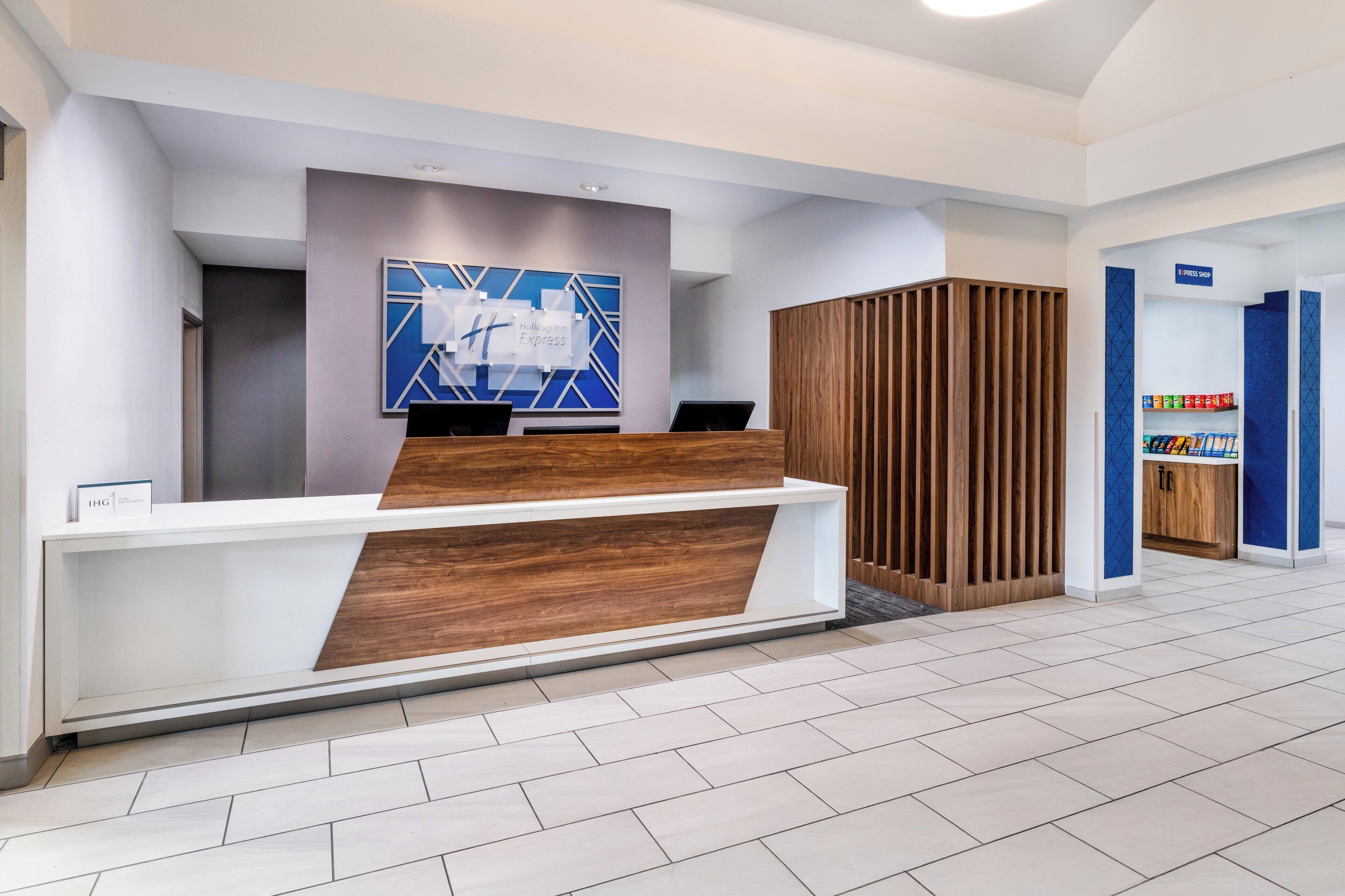 A modern reception desk with a wooden finish and a blue geometric wall art piece above it.