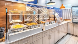 Un buffet de petit-déjeuner proposant différentes sections, chacune étant clairement indiquée, avec des œufs brouillés, des omelettes au fromage et des pommes de terre.